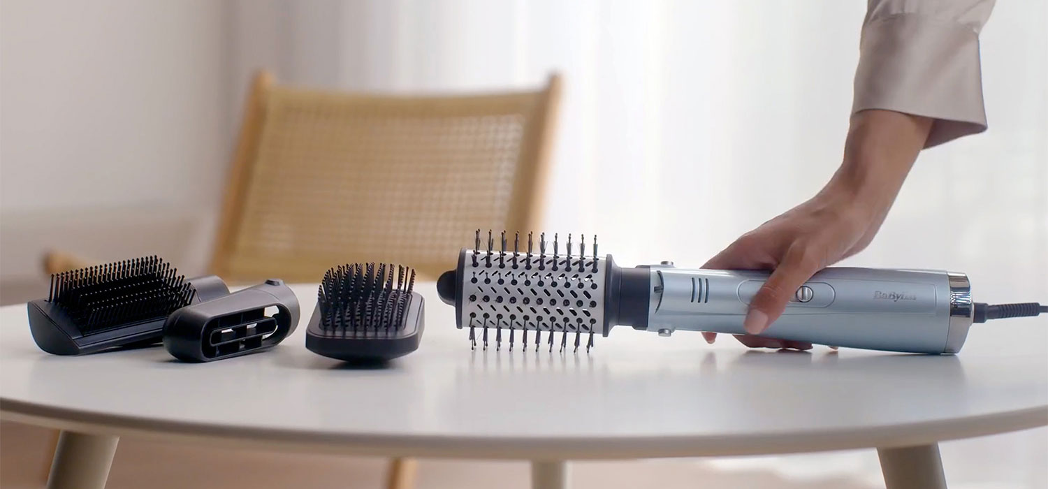 De Kracht en Technologie van Babyliss Apparaten – Een Gedetailleerde Gids Hand die een Babyliss haarborstel van de tafel opraapt