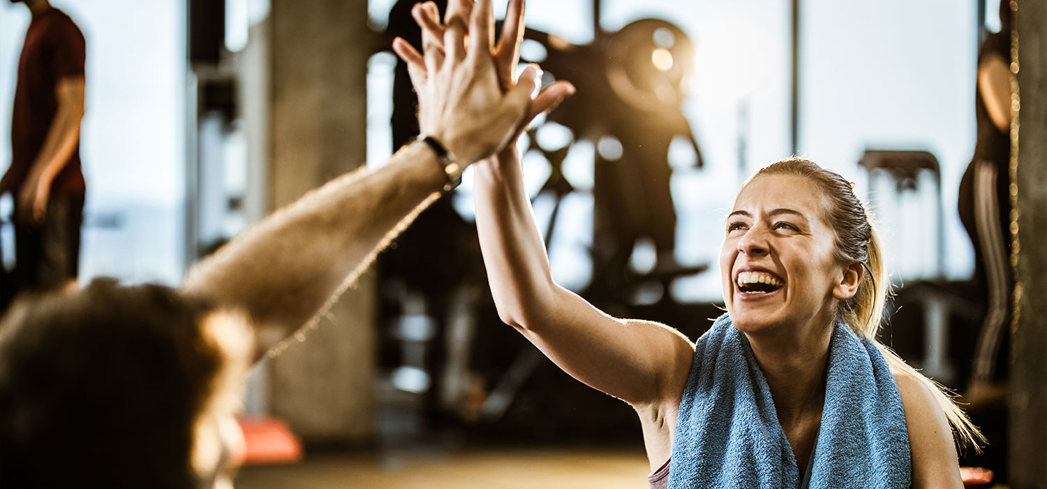 Fitness : Tips om gemotiveerd te blijven voor uw fysieke en mentale fitheid Lachende vrouw in sportkleding die iemand op de hand klopt