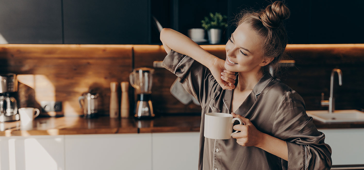 264-luxe-en-confort Vrouw drinkt koffie en rekt zich uit in haar keuken