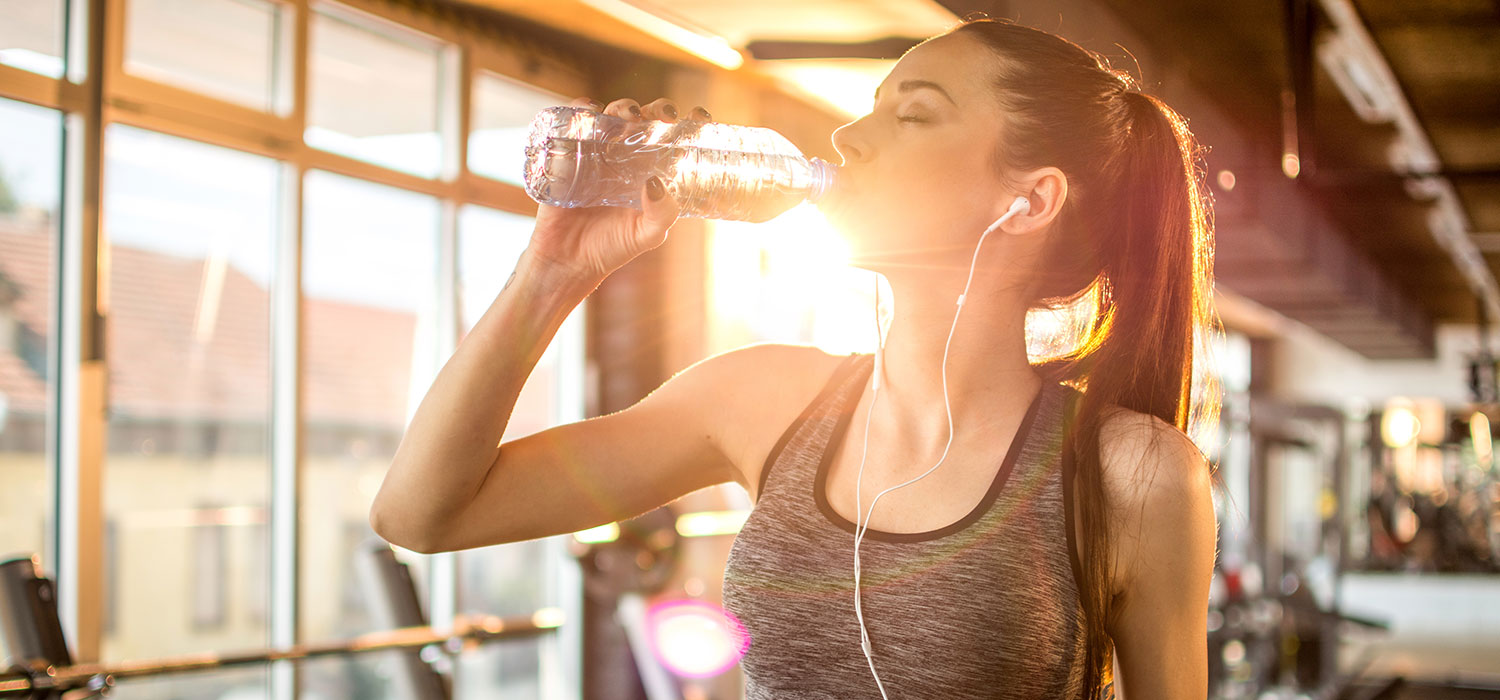 Het belang van hydratatie bij sportbeoefening Vrouw drinkt water na het sporten
