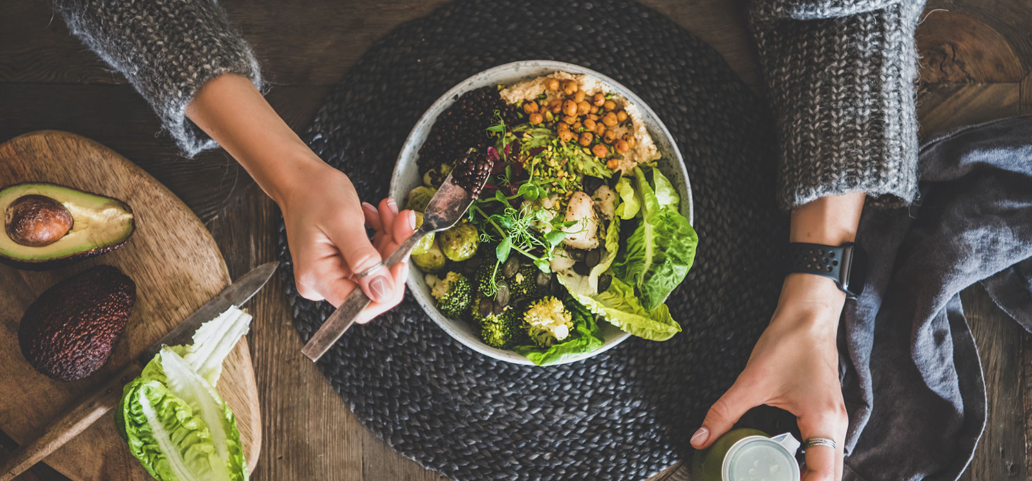De 10 voedingsmiddelen die je moet opnemen voor een optimale gezondheid Vrouw die een salade eet