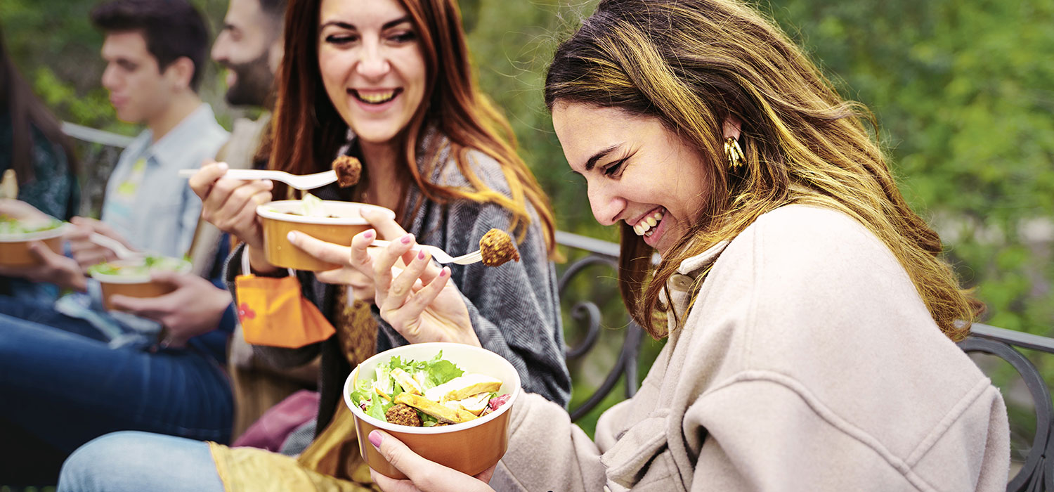 Fast food, fast good Vrouw eet een poke bowl met haar vrienden
