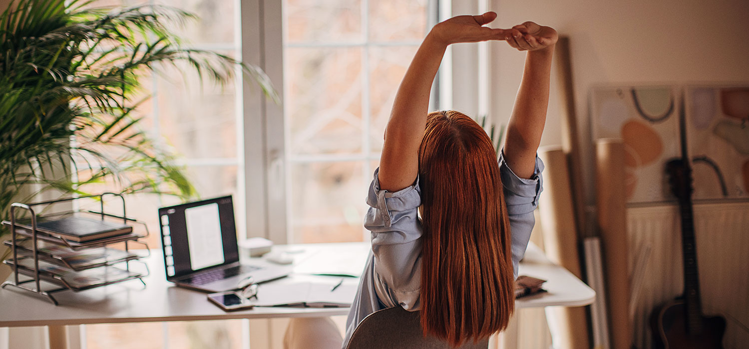 Ouch, verlicht de kleine pijnen Vrouw rekt zich uit in haar stoel aan haar bureau