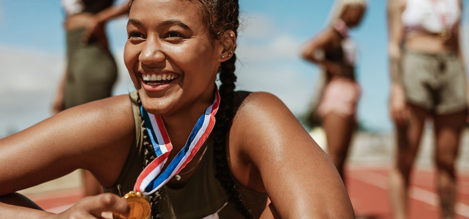 Ontdek de geschiedenis van alle sporten Lachende vrouw met gouden medaille