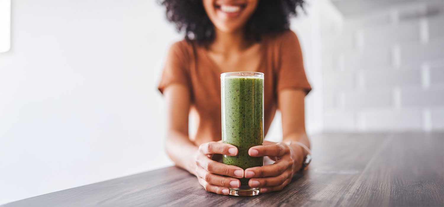 Effectieve detox tips voor een gezond lichaam Een lachende vrouw met een groene smoothie