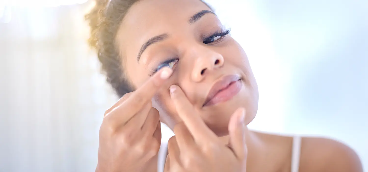 Voordelen van afwisselen tussen lenzen en bril Vrouwen die contactlenzen dragen terwijl ze in de spiegel kijken