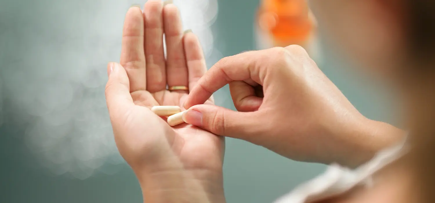 IJzertekort: wanneer innemen en in welke vorm? close-up van de handen van een vrouw die voedingssupplementen vasthoudt