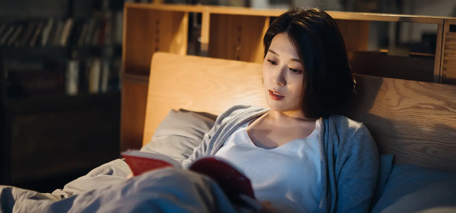 Het belang van een goede slaaproutine Vrouw leest in bed