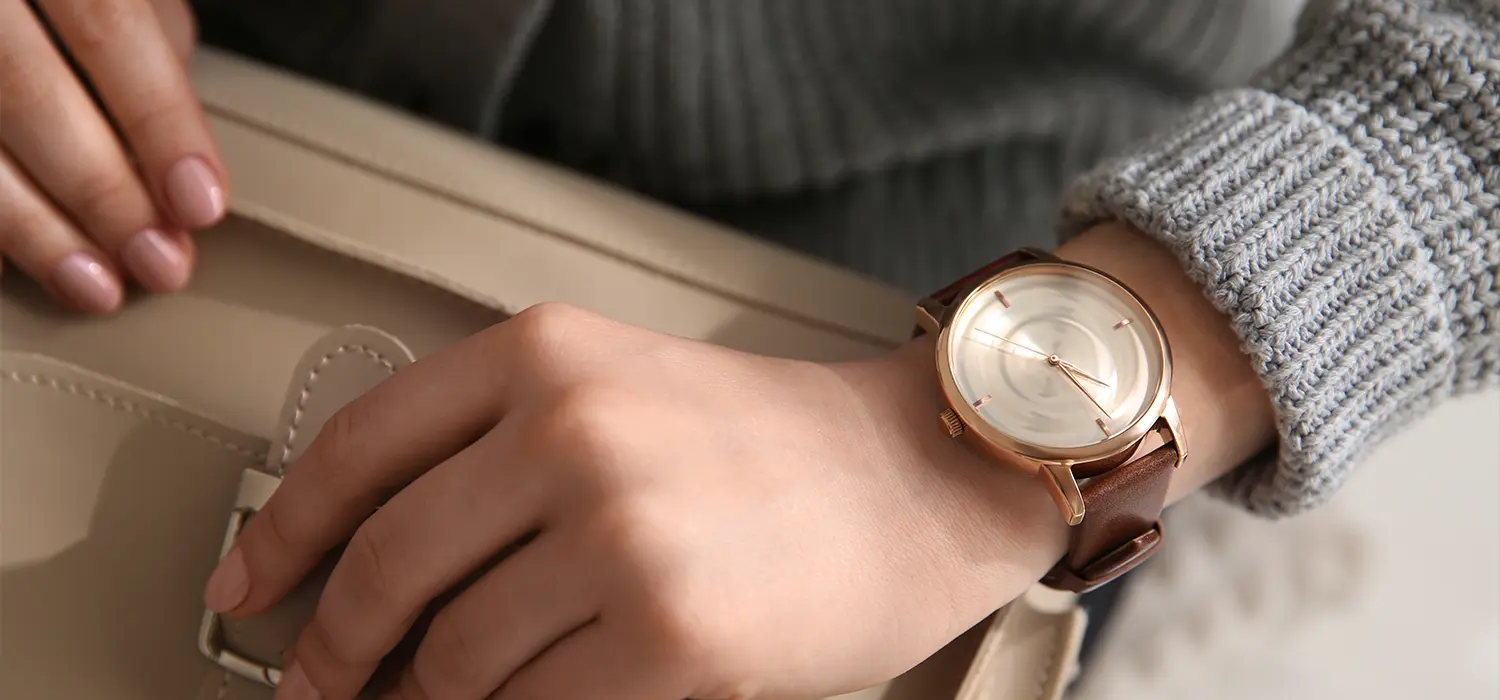 Maak je look compleet met accessoires Zoom in op de handen van een vrouw die een tas vasthoudt en een horloge draagt