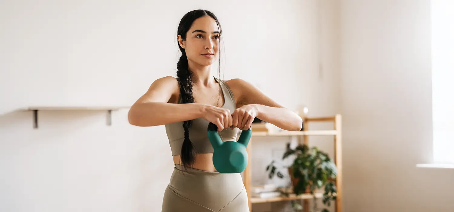 De beste fitness apparatuur voor thuis Vrouw gebruikt een kettlebell thuis