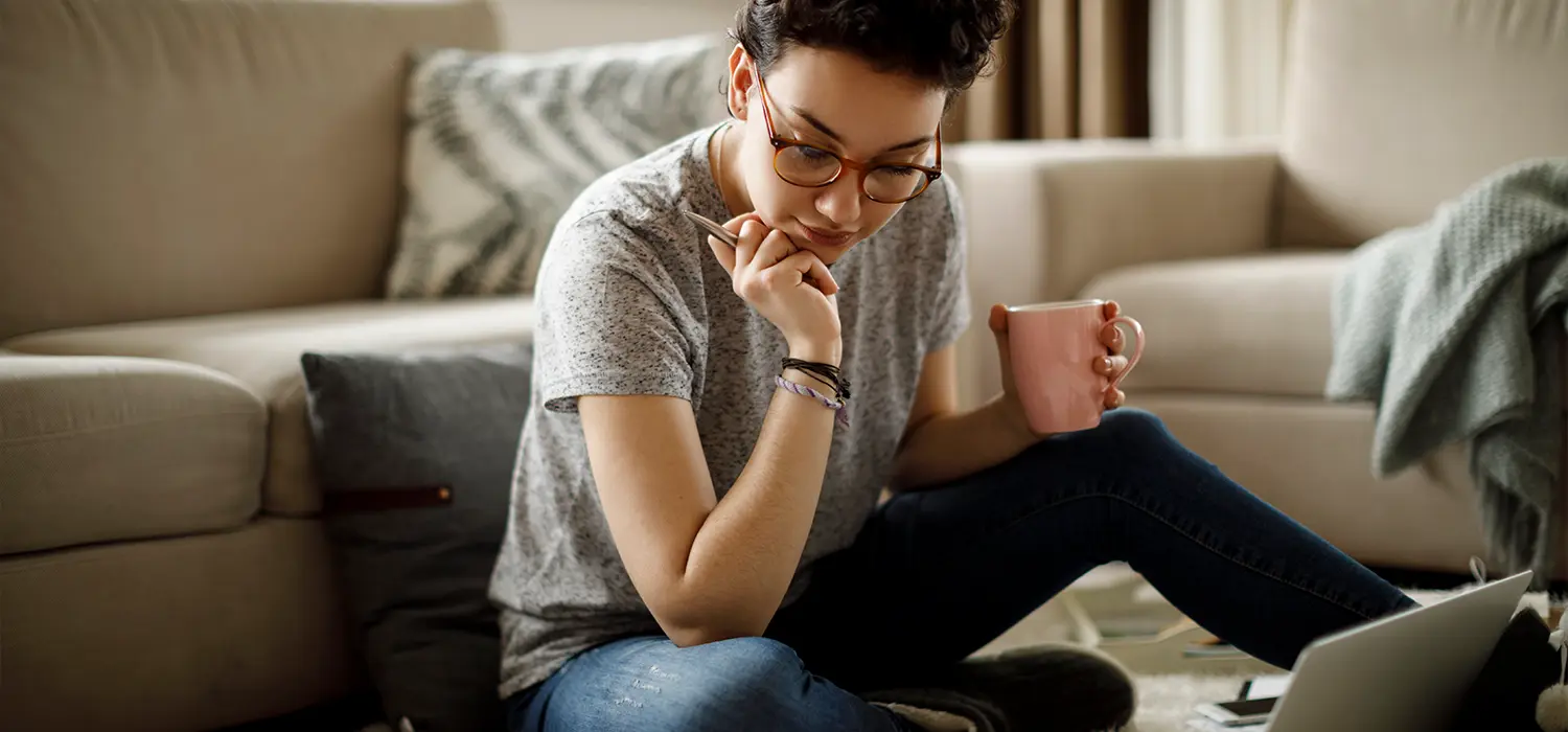 Waarom we ons niet kunnen concentreren: de 9 onzichtbare vijanden van focus een geconcentreerde vrouw aan het werk, zittend op de vloer van haar woonkamer