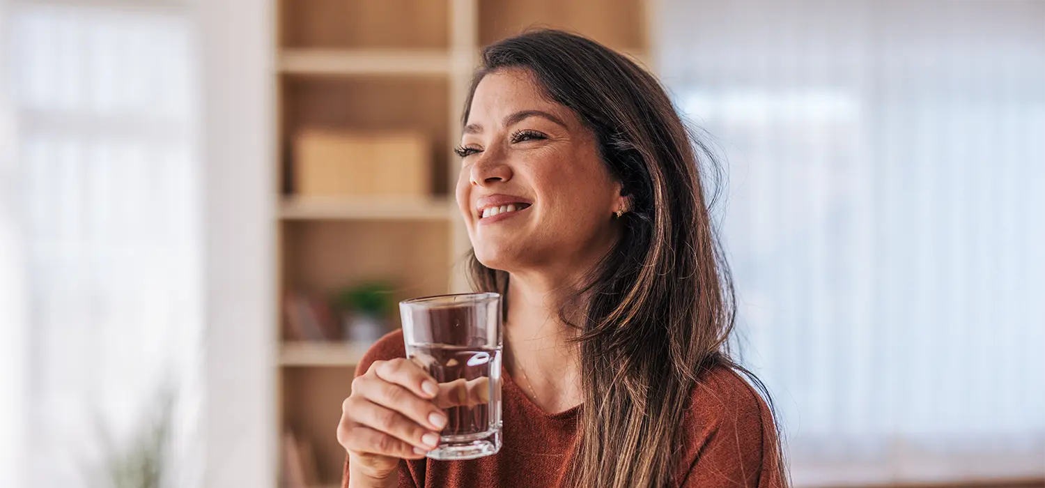 Vochtretentie, lymfatische en veneuze circulatie om zwellingen te verminderen Lachende vrouw die een glas water drinkt
