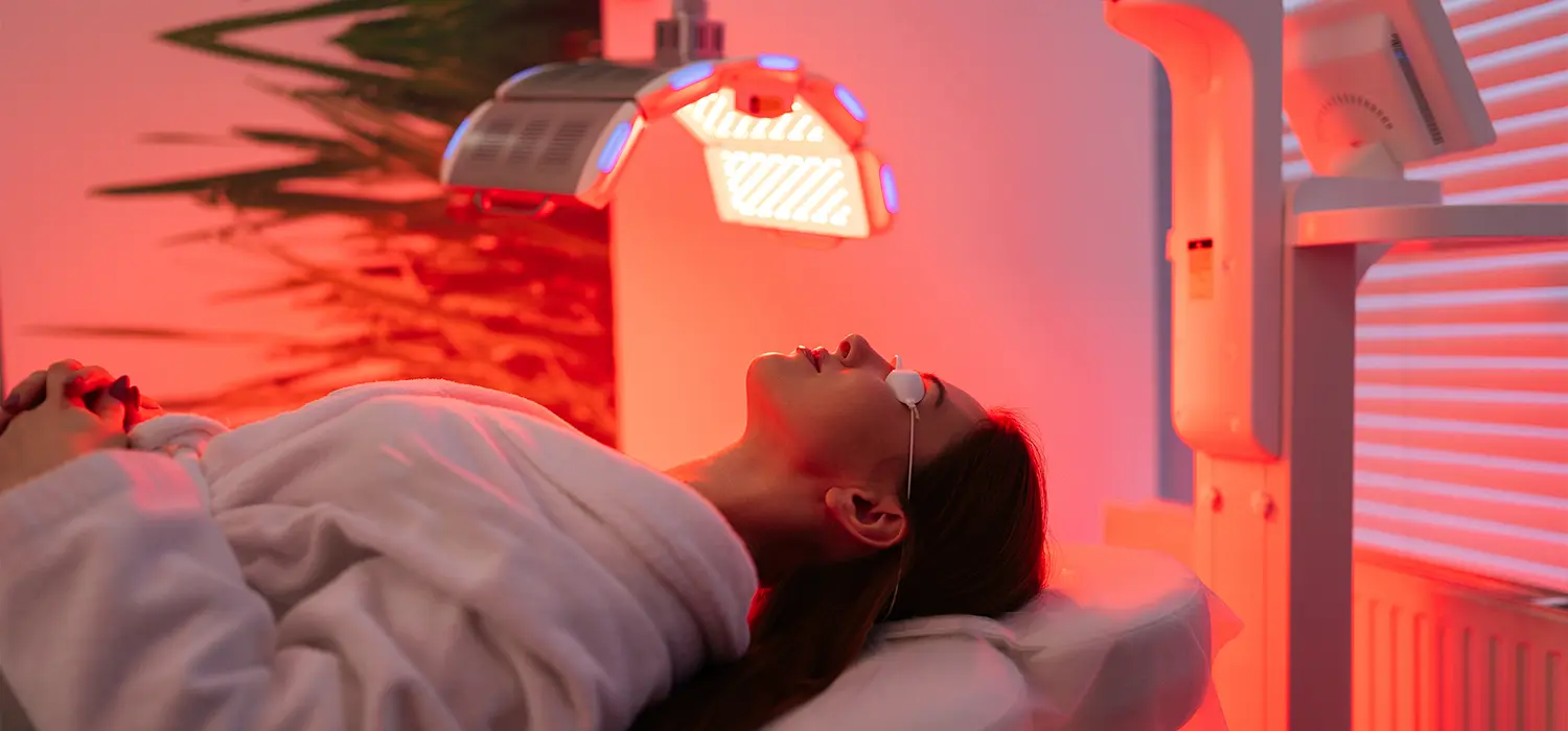 De esthetische behandelingen die écht werken voor de hormonale huid. Vrouw die een LED-behandeling krijgt in een schoonheidssalon